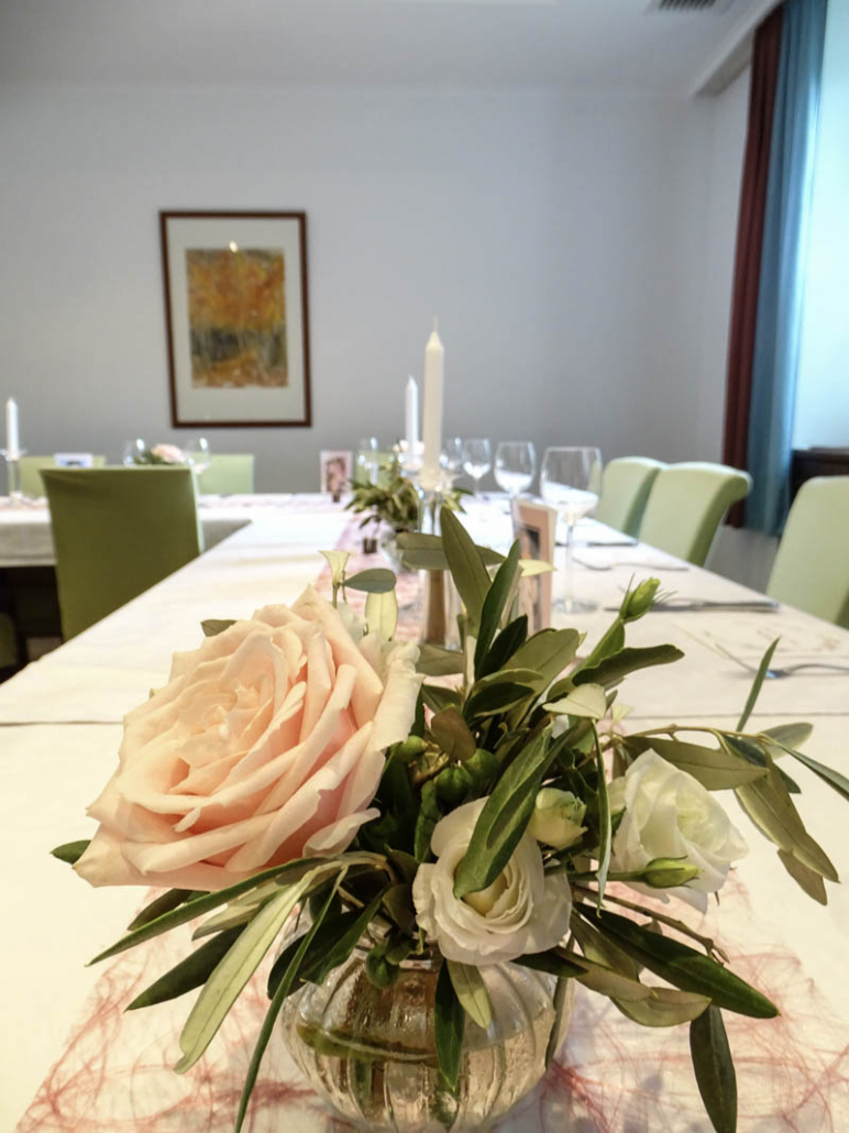 weiße Rosen und grüne Zweige als Tischdekoration
