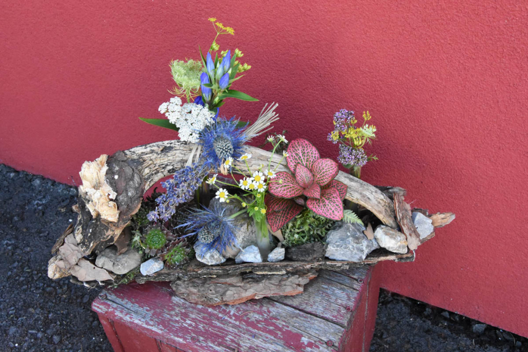 Holzgesteck mit Blumen und Steinen geschmückt