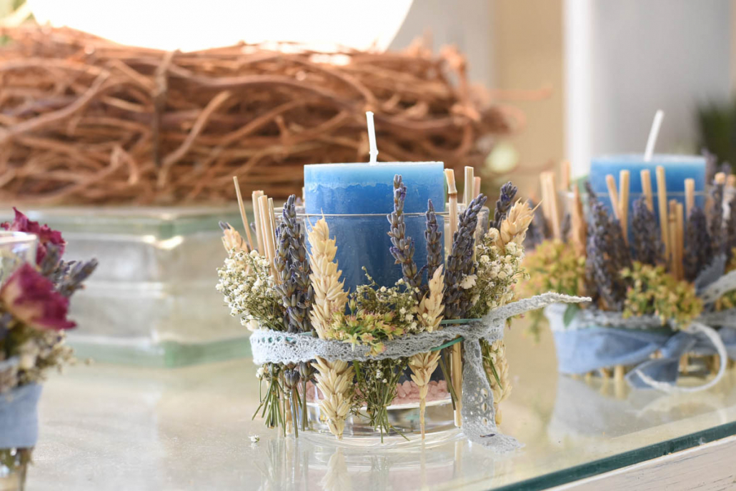 blaue Kerze im Glas, mit Trockenblumen umbunden