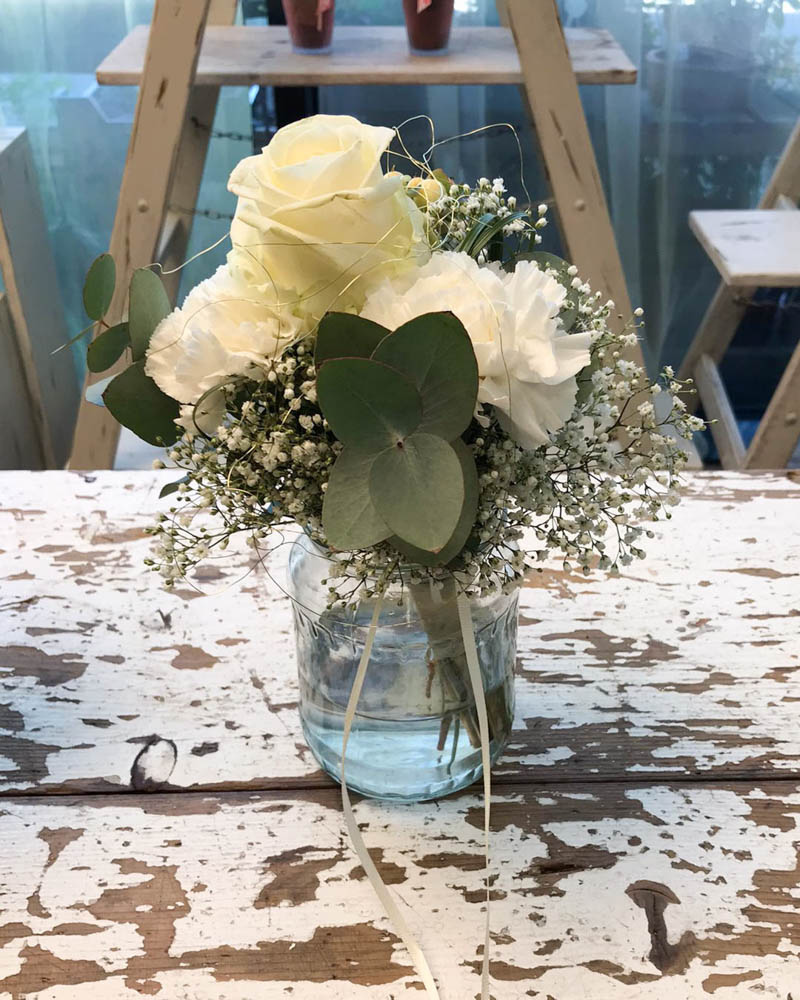 kleiner Blumenstrauß mit weißen Rosen im Glas